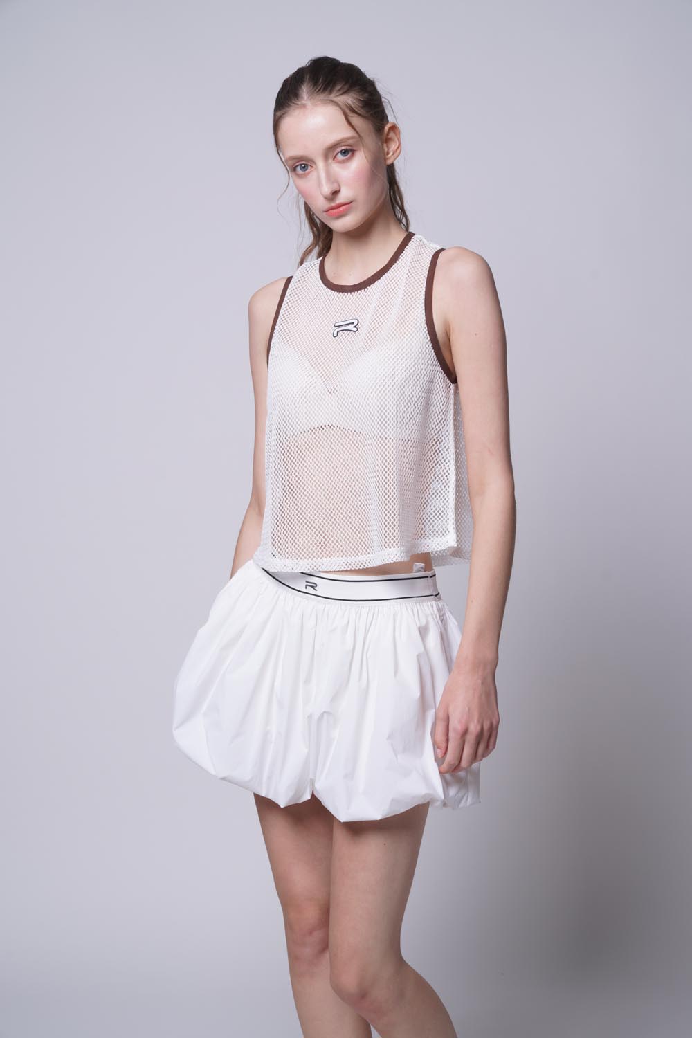 Female model looking straight view wearing Ramsports Court Flow Scoop Tank in white