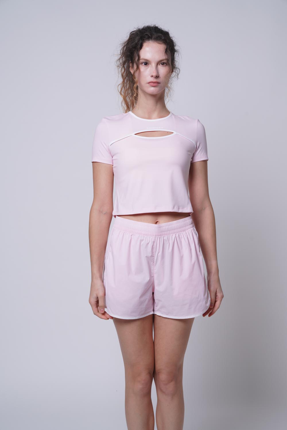 Female model posing with a straight body, wearing Ramsport arcBand crew tee in pink