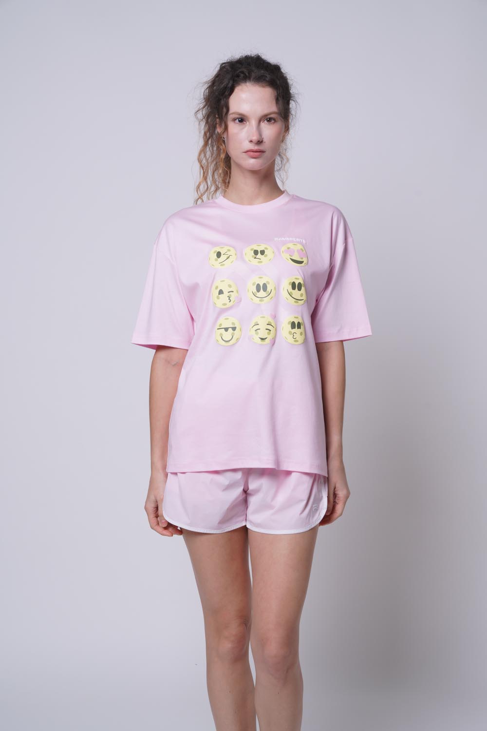 Person wearing Ramsports Court Moods Icon Grid T-shirt in white with smiley face designs on a plain background