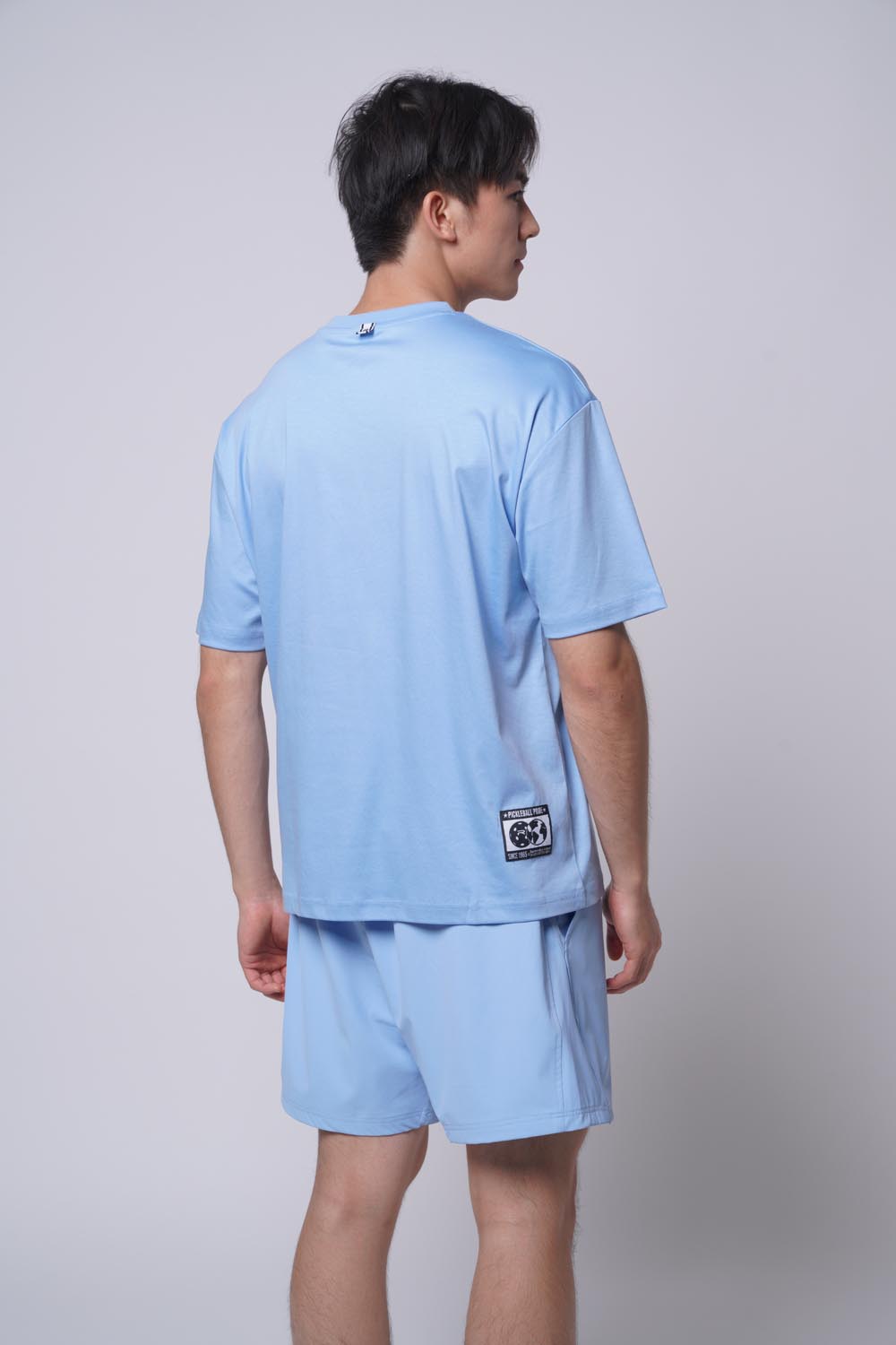 Asian male model standing facing away wearing Ramsports Court Moods Icon Grid T-shirt in blue