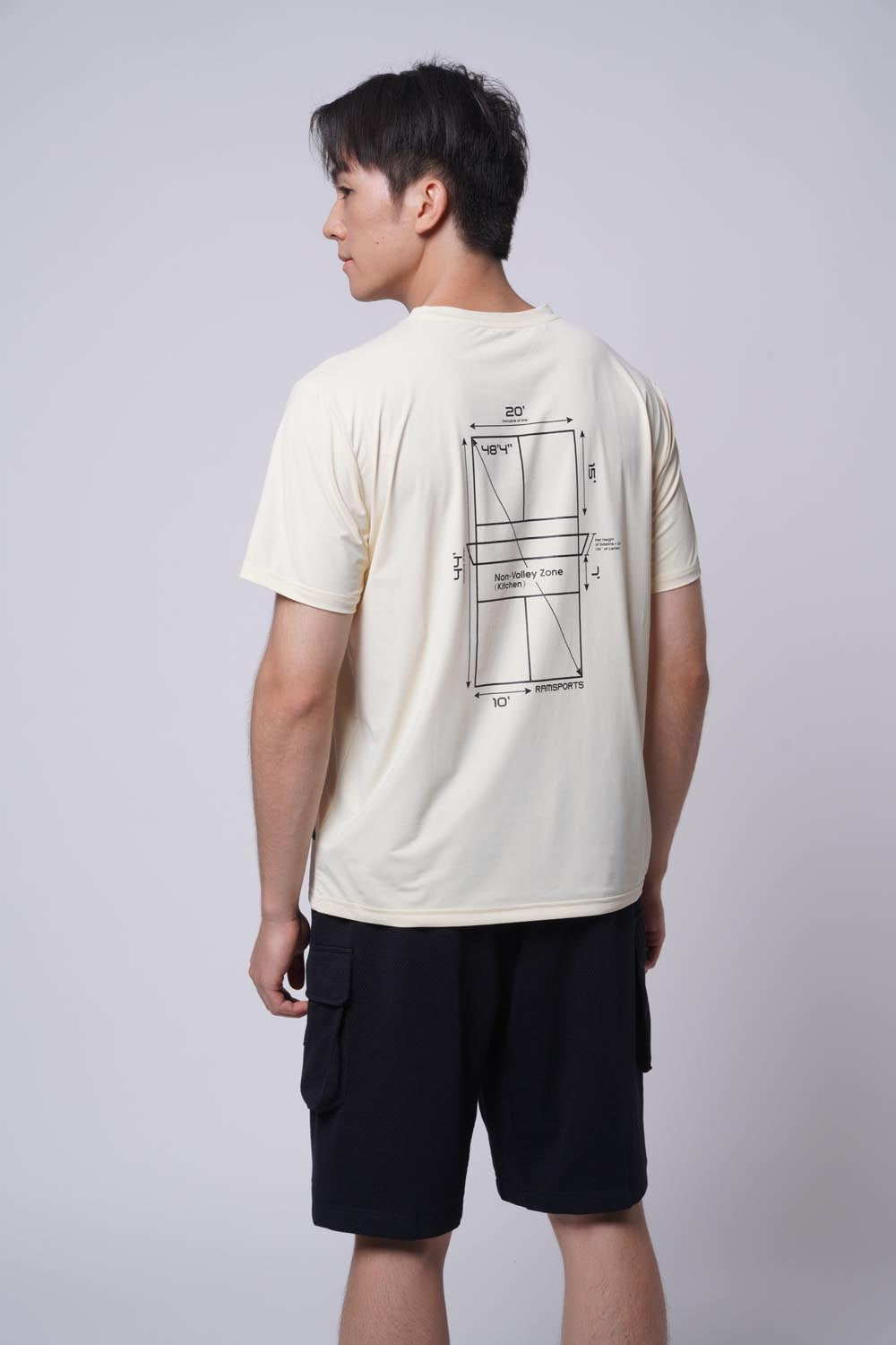 Male model displaying the back of the beige Ramsports Playbook Court Diagram tee on a gray background