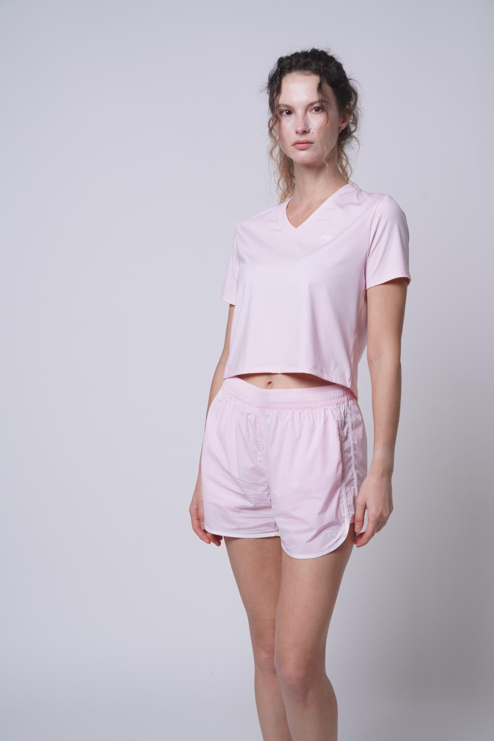 female model standing as she's wearing Ramsports Flow Panel Split-Hem Short in pink and a pink shirt