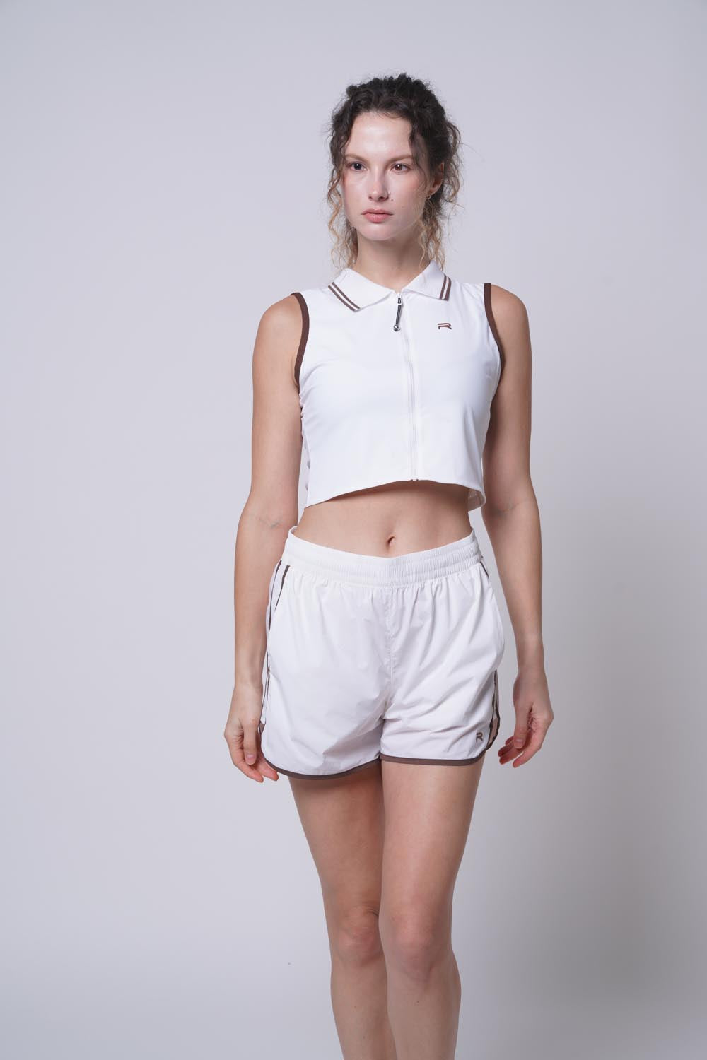 Female model wearing Ramsports serve zip crop polo in white
