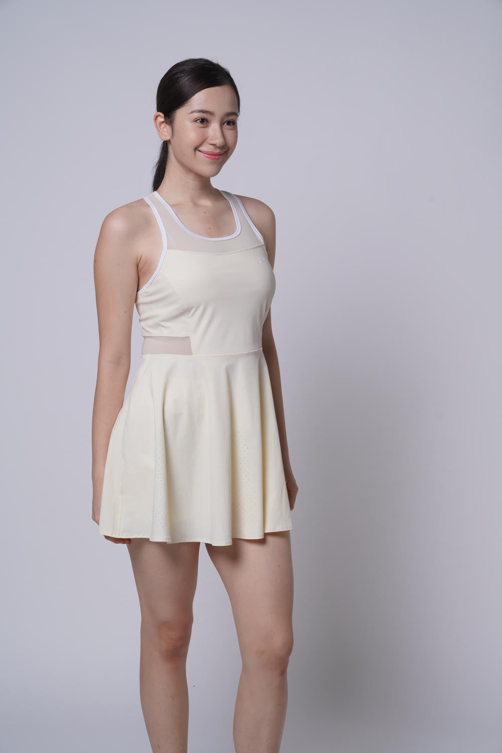 Asian female model smiling as she's wearing the Ramsports Racer Flare Dress in beige