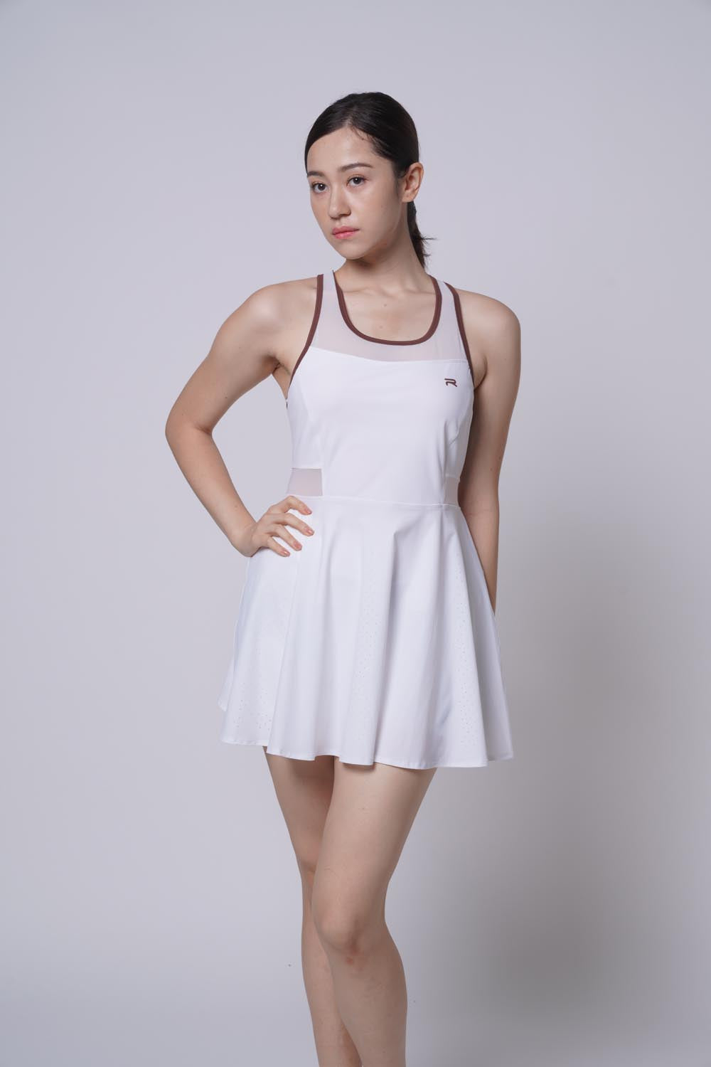 Asian female model with one arm on her waist as she's wearing a blue Ramsports Racer Flare Dress.