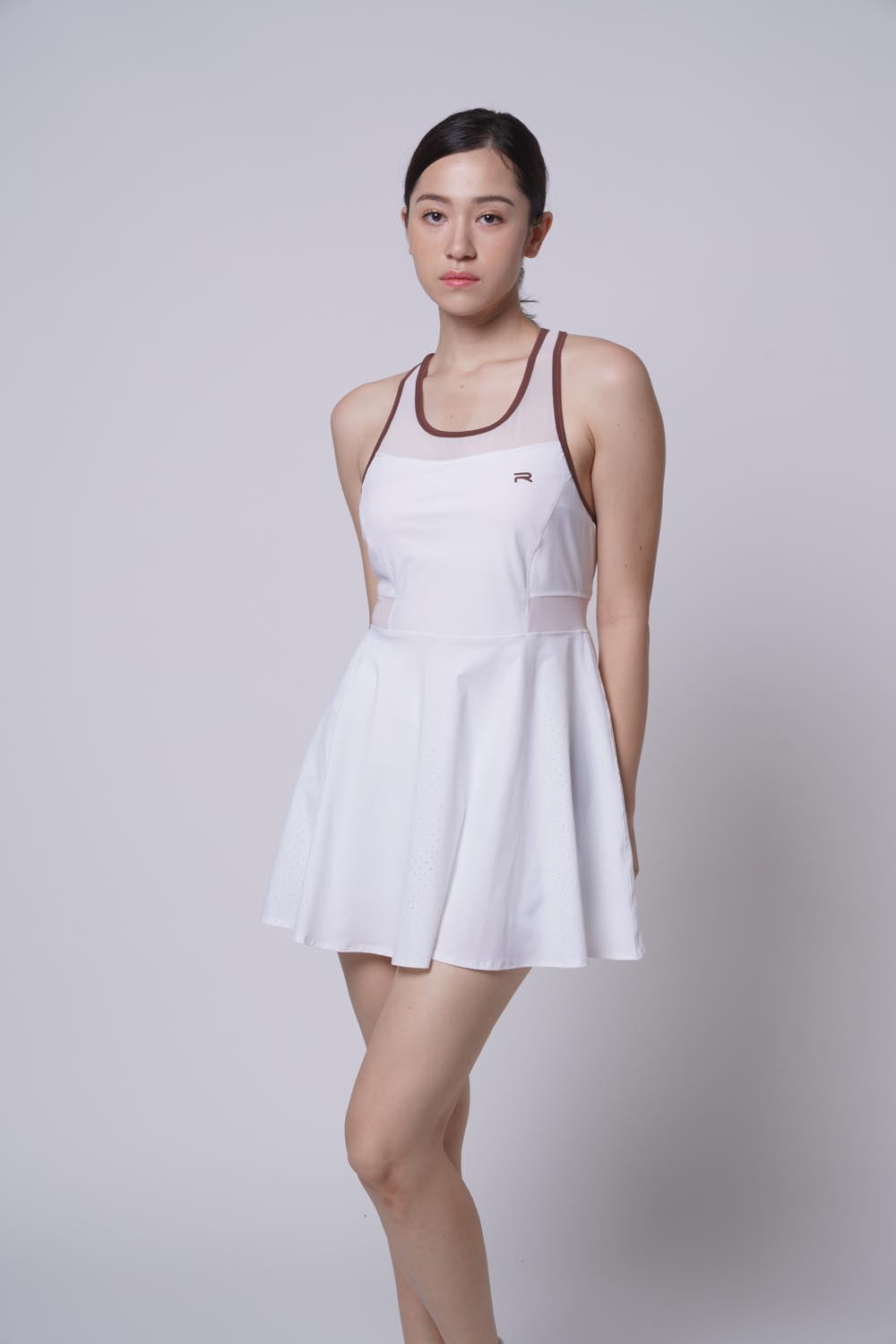 Asian female model with one knee bent forward, wearing a white Ramsports Racer Flare Dress.
