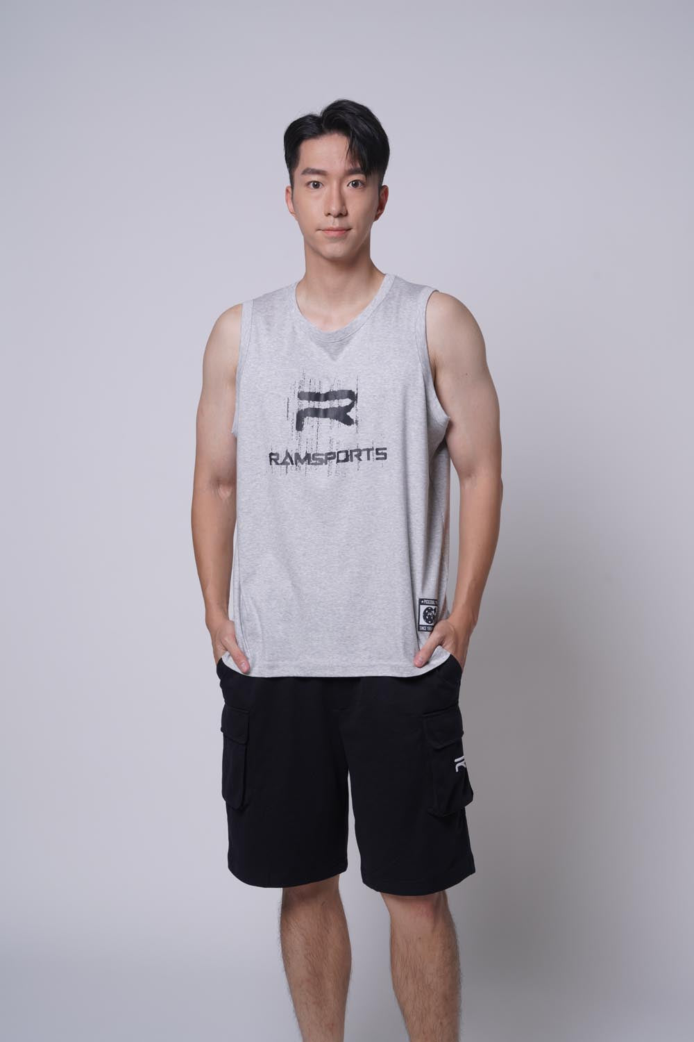 Asian male model wearing Ramsports repMark tank in gray with hands on pockets