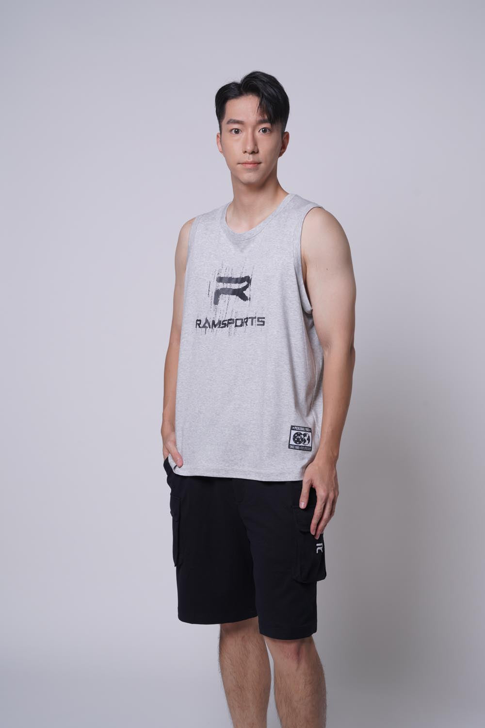 Asian male model looking at the camera, wearing Ramsports repMark tank in gray with one hand on pockets