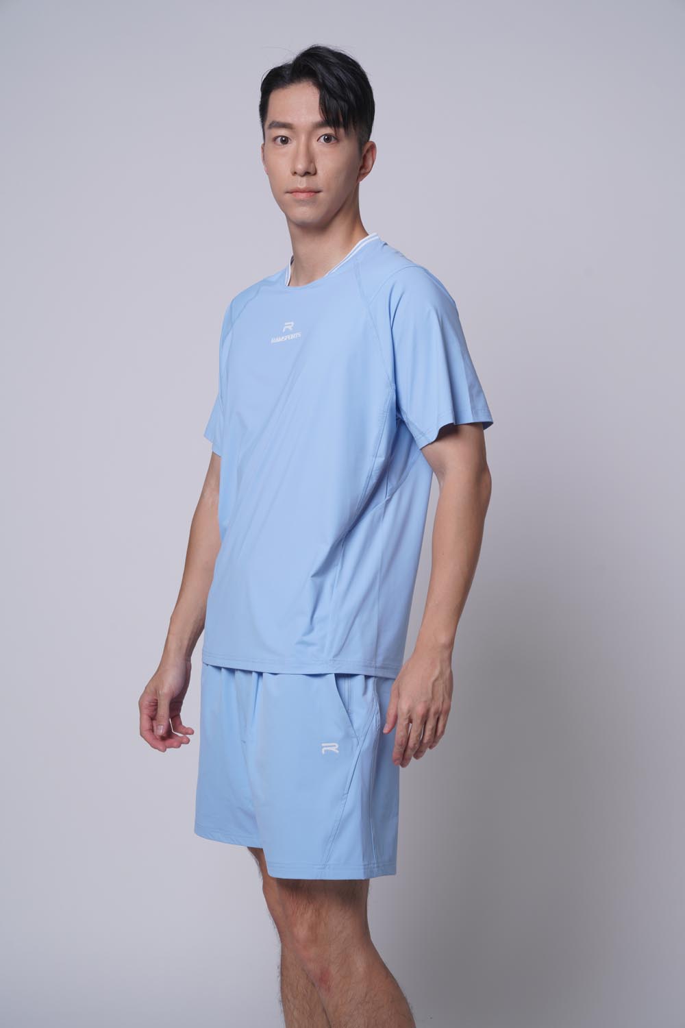 Asian male model standing facing sideways wearing ramsports Edge Line Raglan Tee in blue