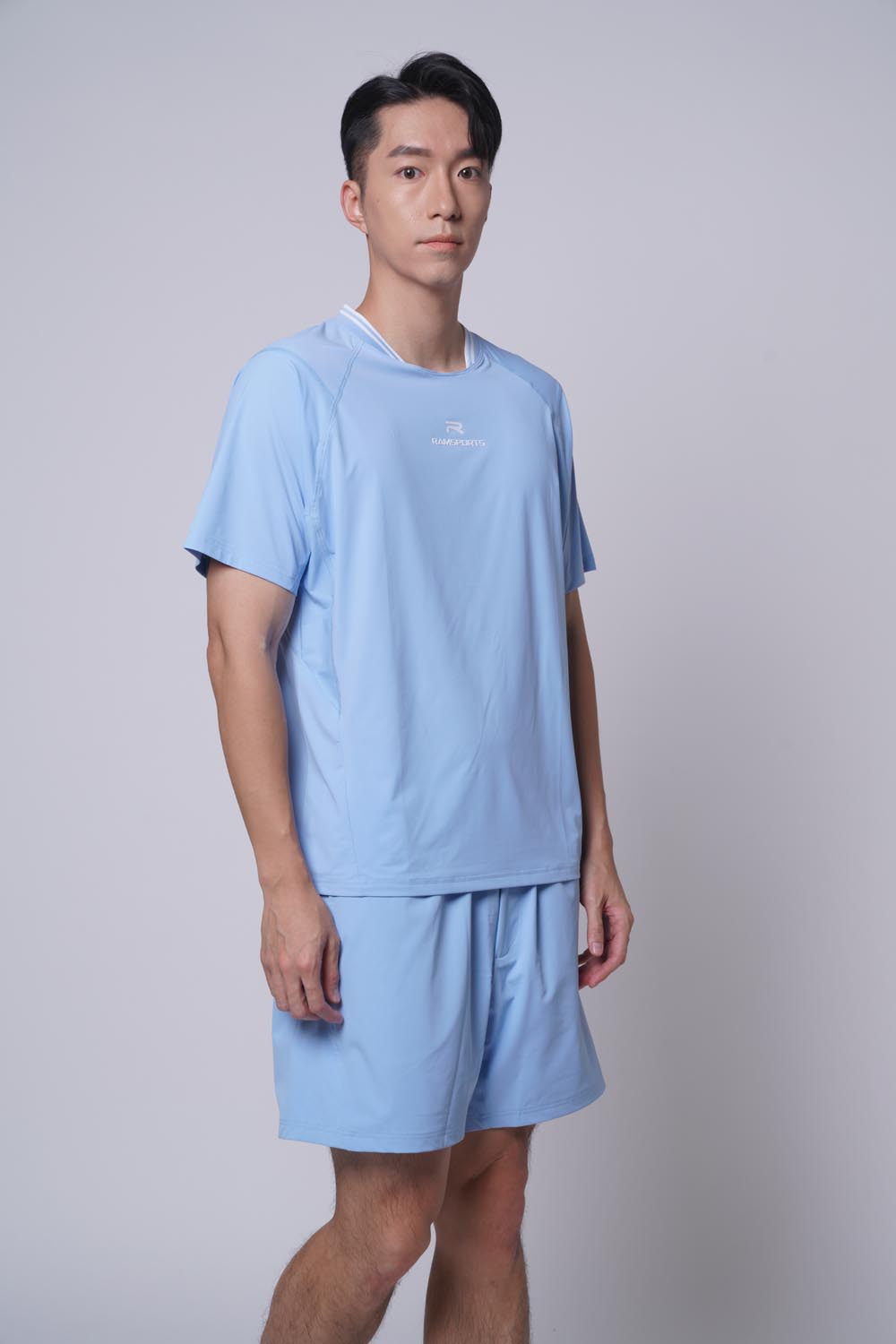 Asian male model standing facing left sideways wearing ramsports Edge Line Raglan Tee in blue