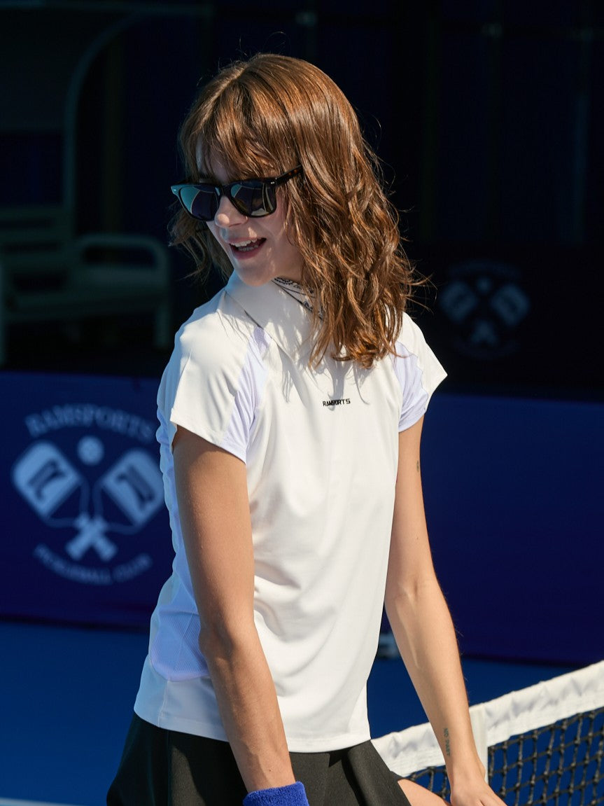 Female model facing away from the camera, wearing a white Ramsports AirFlow Mesh Polo, a white skort, and sunglasses