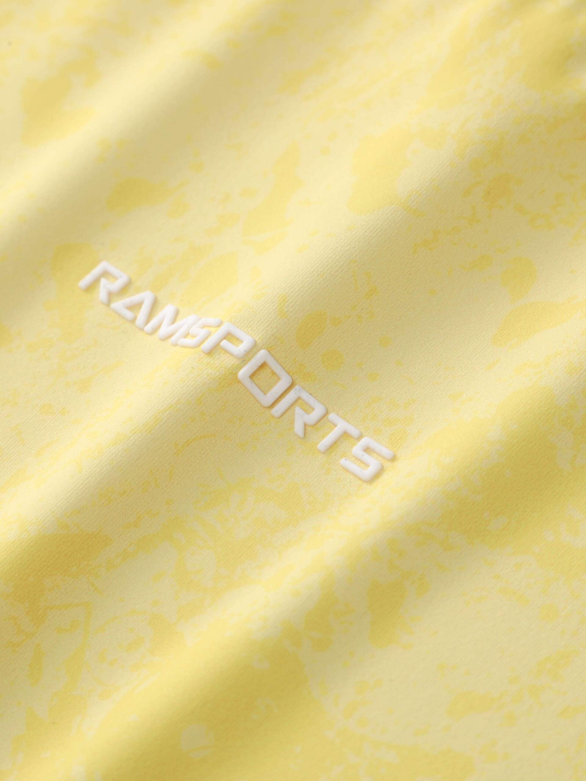 Close-up of the white Ramsports logo printed on the yellow Ramsports CoolDry Marble Print Tee