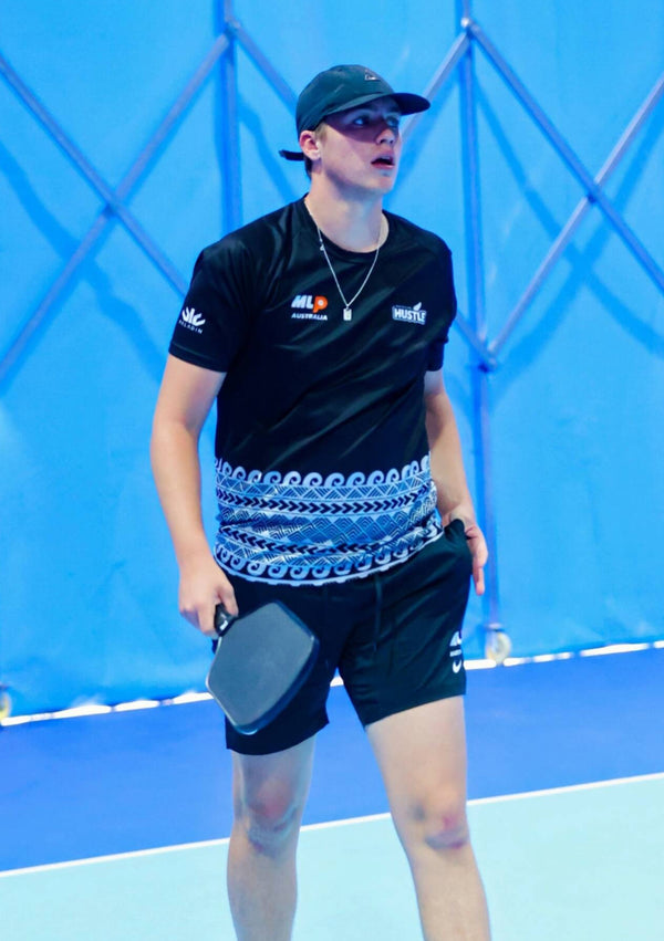 Western male player walking or in motion, looking away from the camera while holding the Ramsports Ignis Pro Pickleball Paddle