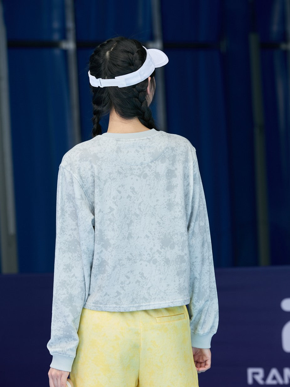 Smiling Asian female model facing backward, wearing a gray Ramsports EcoSoft Marble Print Crop Sweatshirt and yellow shorts