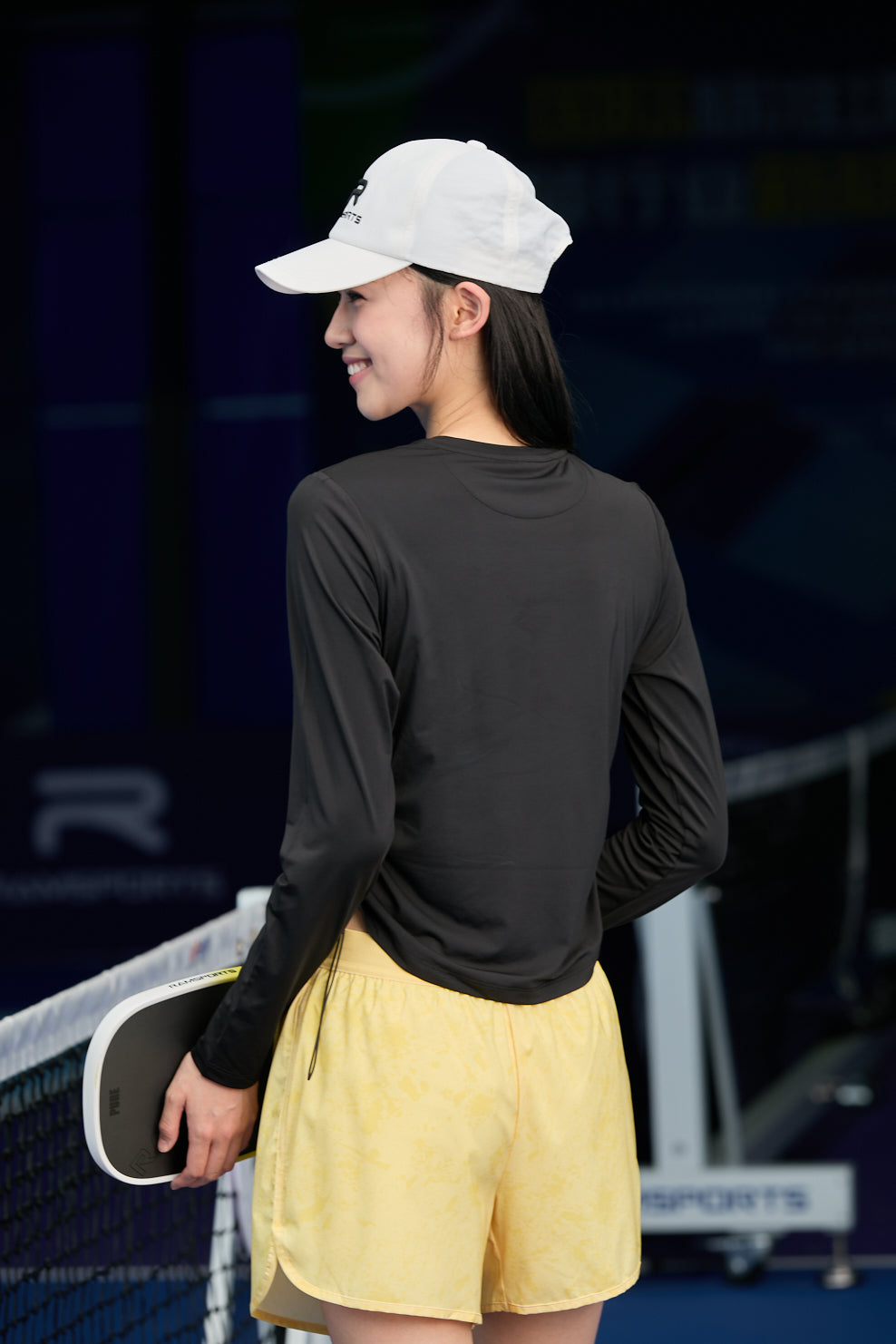 Model facing backwards wearing yellow Ramsports FlexTek Marble Print Shorts and a black long-sleeve top