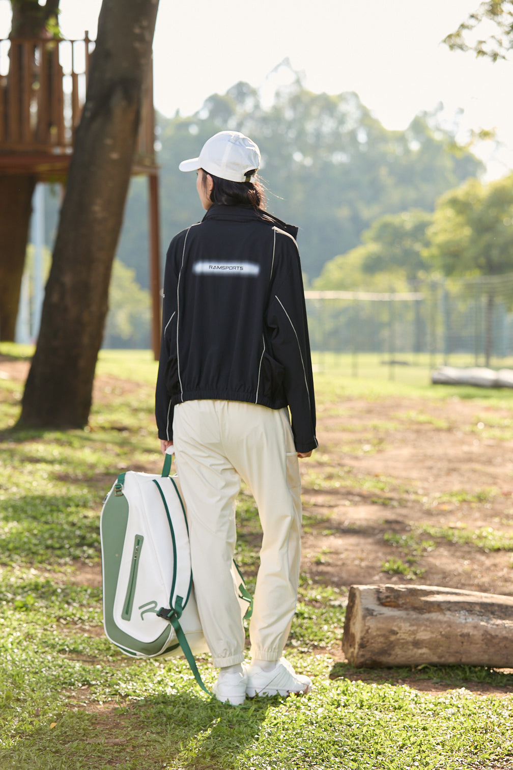 Asian female model facing away, wearing khaki Ramsports FlexTek Motion Joggers and holding a white cap and backpack