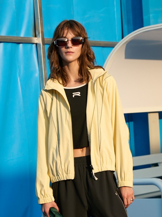 Female model wearing a yellow Ramsports FlexTek Block Jacket paired with black shorts or joggers