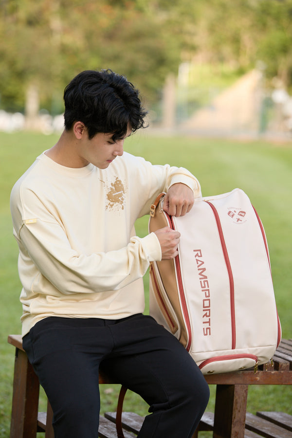 Asian male model sitting down while opening the Ramsports Heritage DuoTone Backpack