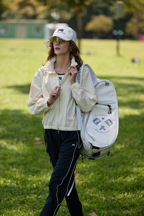 Female model posing as if walking, wearing the Ramsports LiteCarry Arctic Backpack with one strap, while holding the zipper of her jacket with her other hand