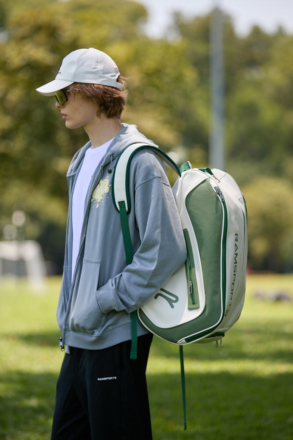 Western-looking Asian male model wearing the Ramsports LiteCarry Olive Trim Backpack with one strap, facing away in a side view