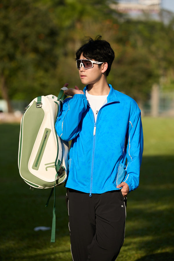 Asian male model wearing a blue jacket, holding the top strap of the Ramsports LiteCarry Olive Trim Backpack
