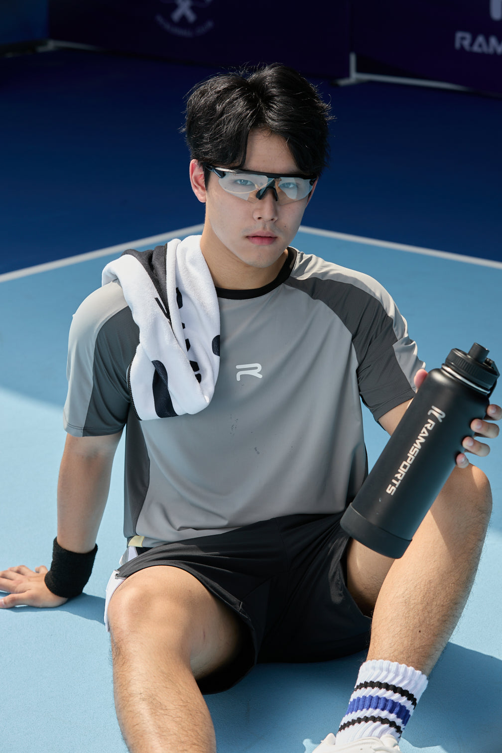 male model sitting in court holding his Ramsports black tumbler