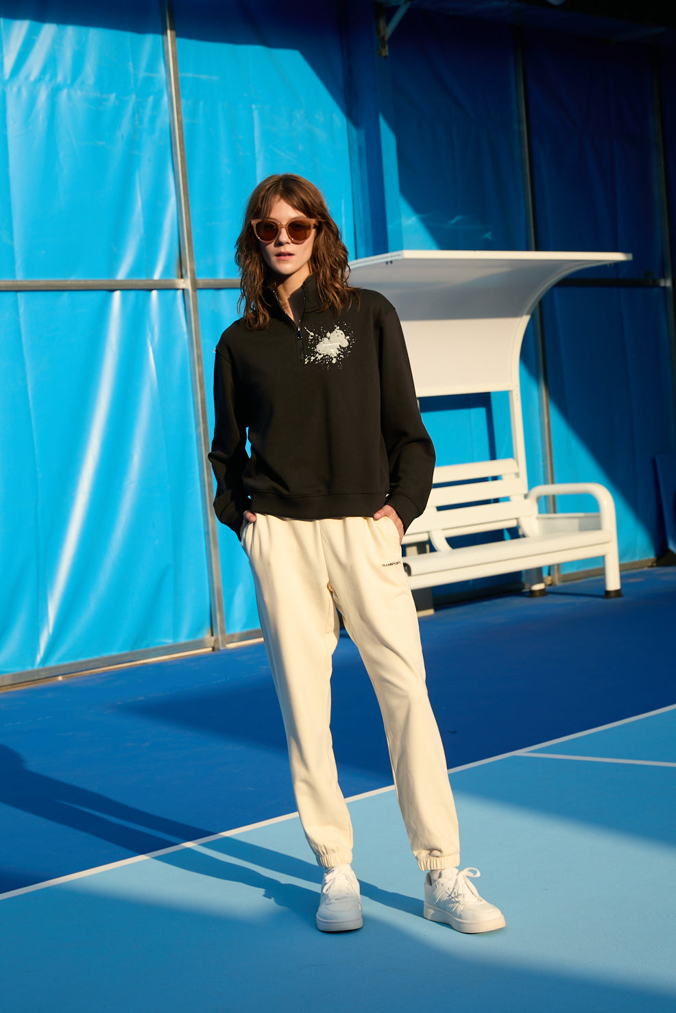 Female model wearing khaki Ramsports EcoSoft Everyday Joggers with a black jacket and sunglasses
