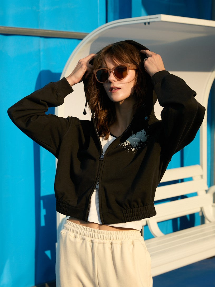 Female model wearing a black Ramsports EcoSoft Logo Hoodie over a white top, with the hood up