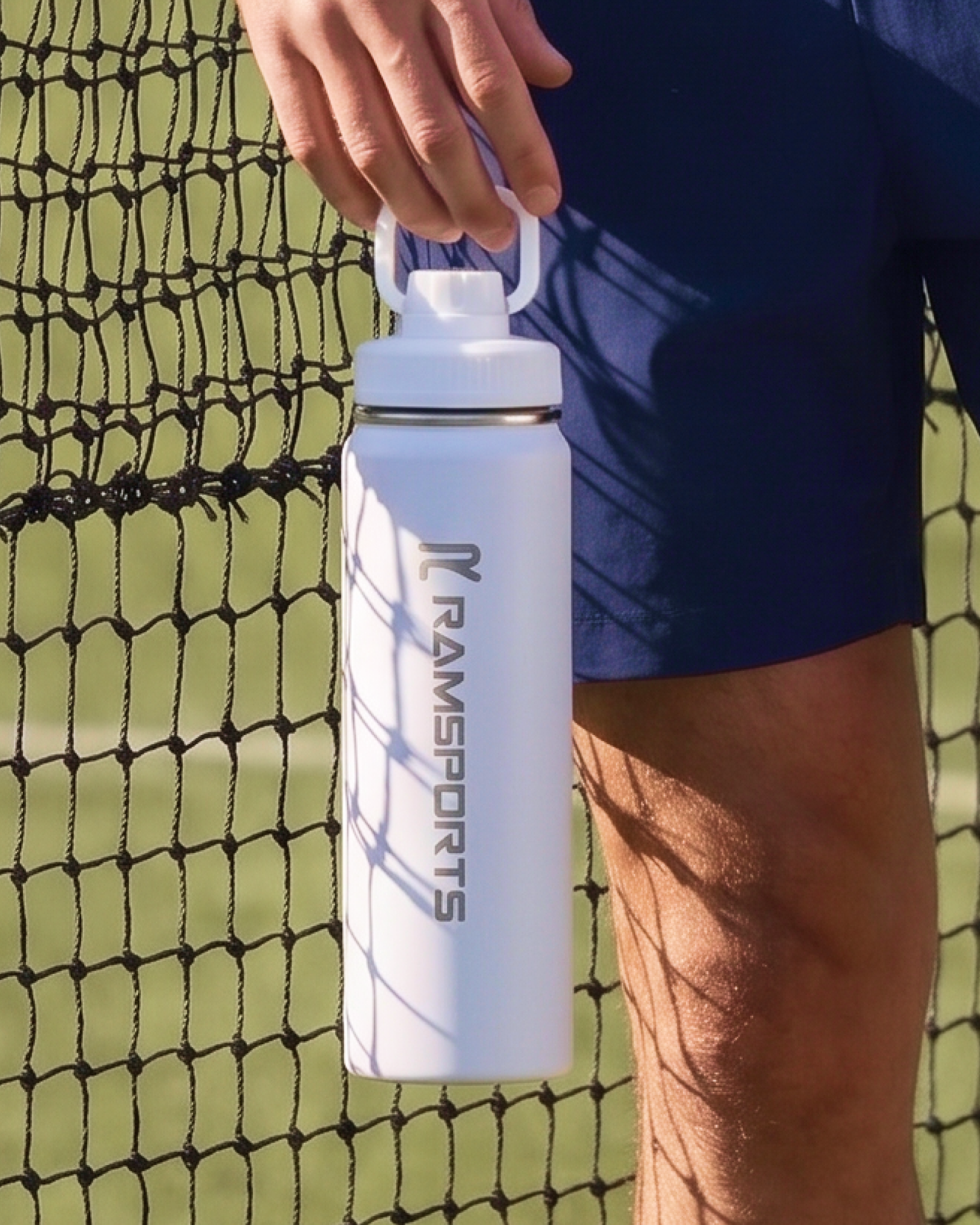 Cropped image of a man holding a Ramsports paddle in his right hand with a towel draped over his shoulder.