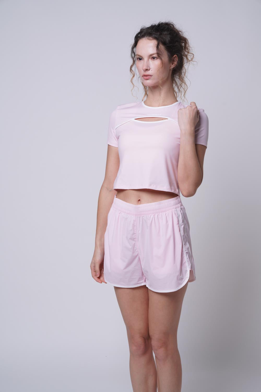Female model with her hand on her shoulder looking away, as she's wearing Ramsport arcBand crew tee in pink