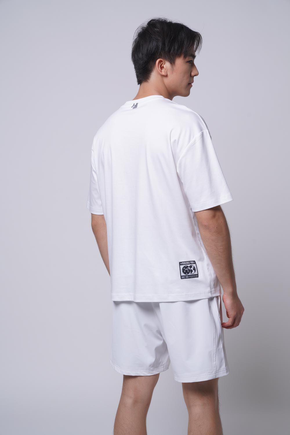 Asian male model standing facing away wearing Ramsports Court Moods Icon Grid T-shirt