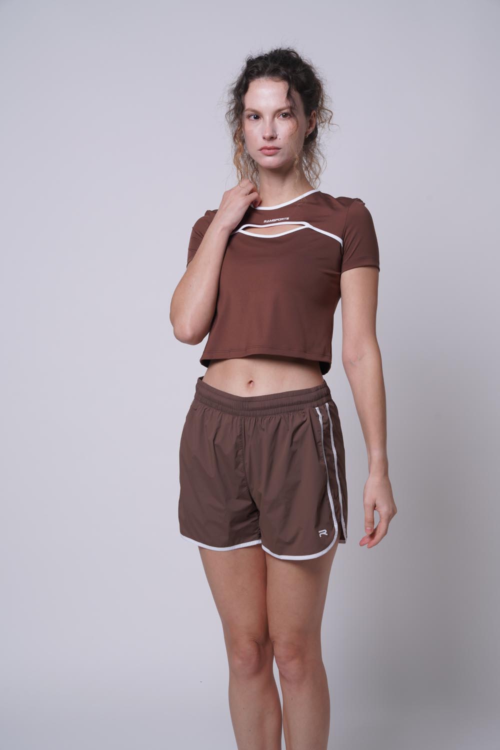 Female model with her hand on her shoulder wearing Ramsport arcBand crew tee in brown
