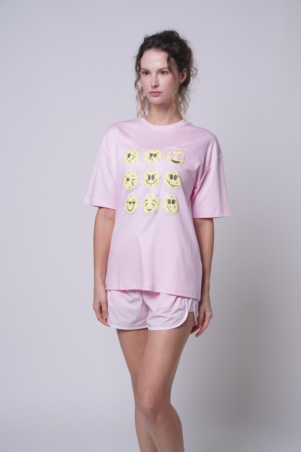 Asian female model standing sideways wearing Ramsports Court Moods Icon Grid T-shirt in pink