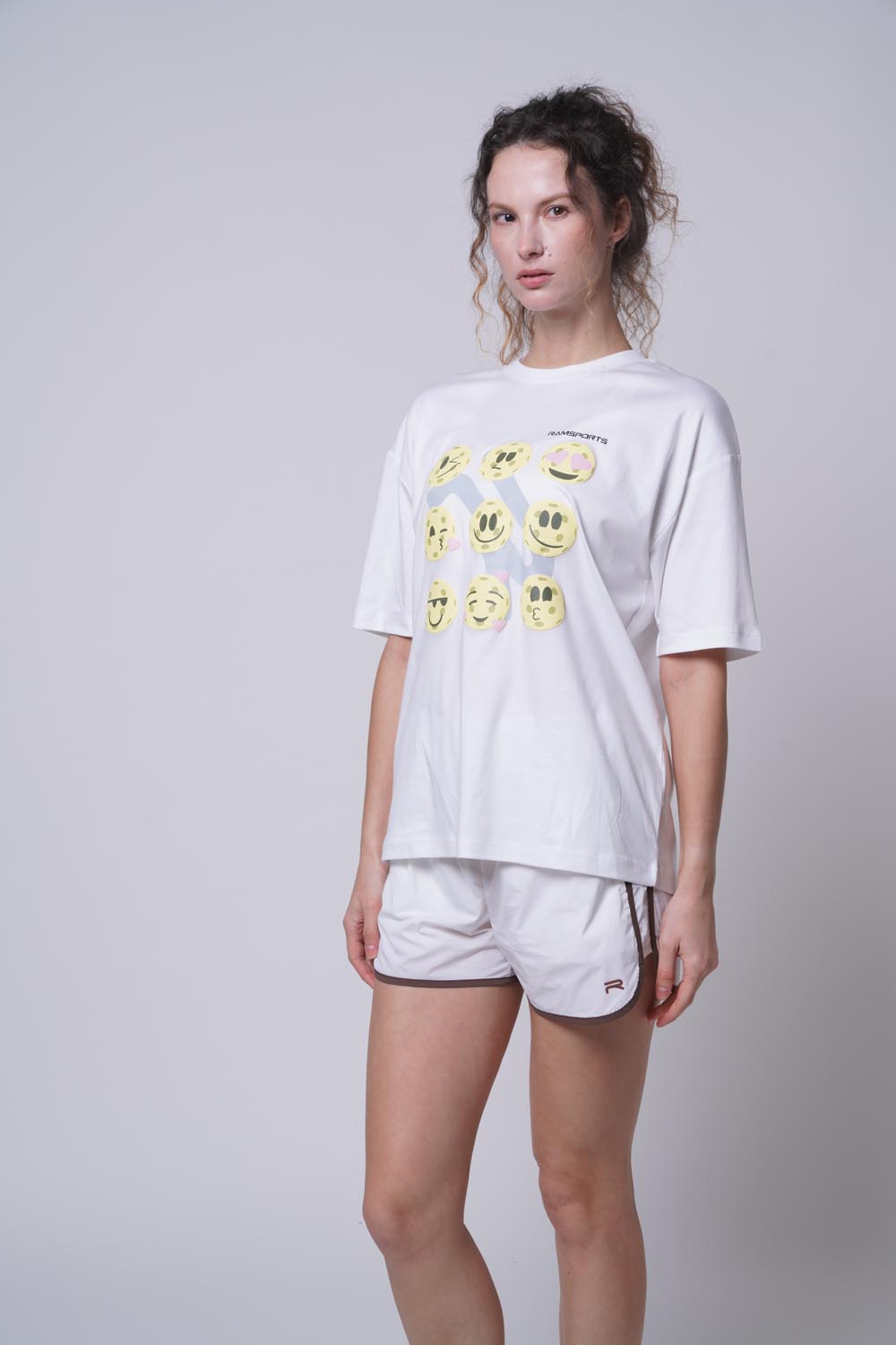 Asian female model standing sideways wearing Ramsports Court Moods Icon Grid T-shirt in white