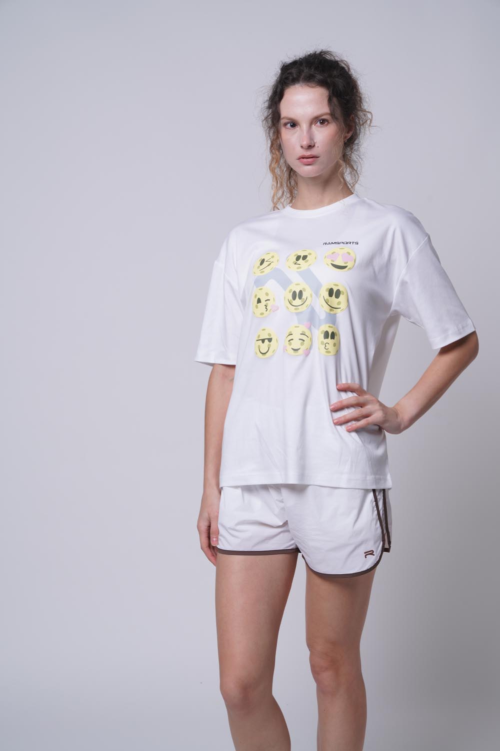 Female model with her hand on her right hip wearing Ramsports Court Moods Icon Grid T-shirt in white