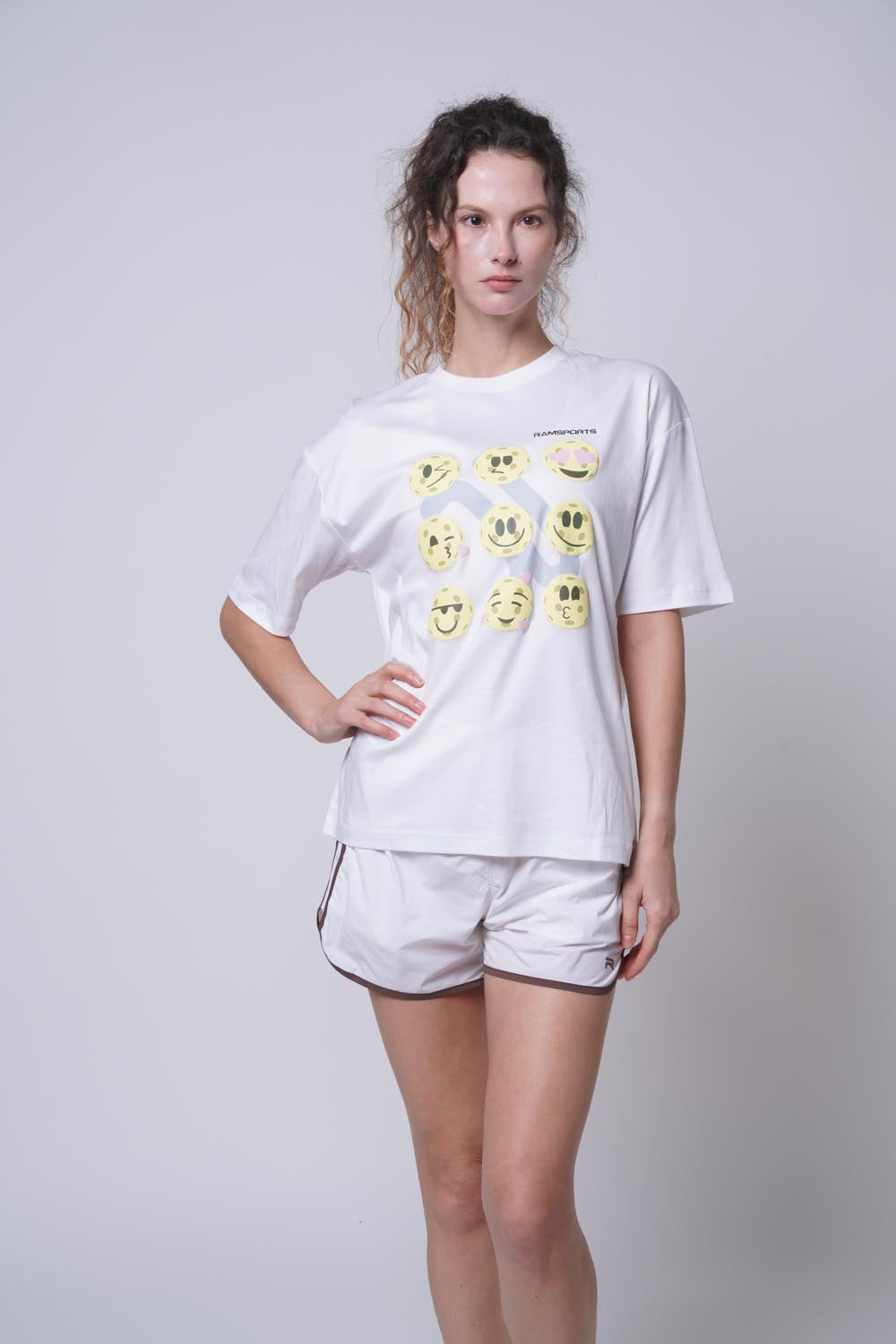 Female model with her hand on her left hip wearing Ramsports Court Moods Icon Grid T-shirt in white