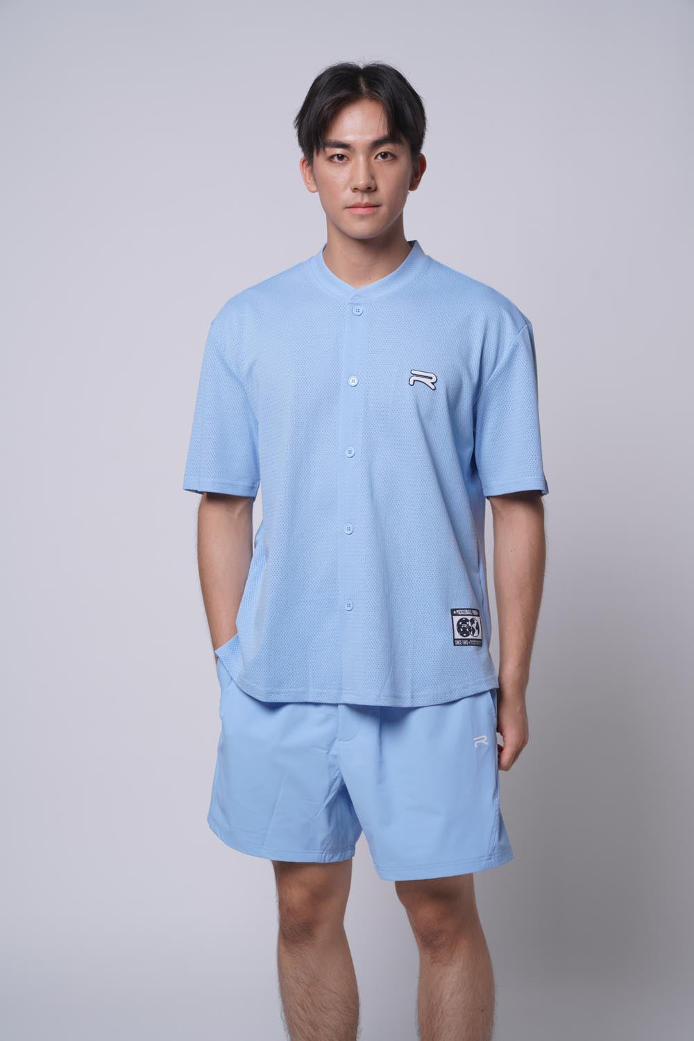Asian male model looking at the camera with one hand one shorts, wearing Ramsports MatchDay Core Short in blue