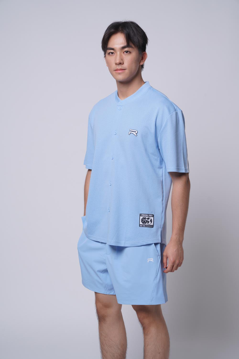 Asian male standing a bit sideway with one hand one shorts, wearing Ramsports MatchDay Core Short in blue