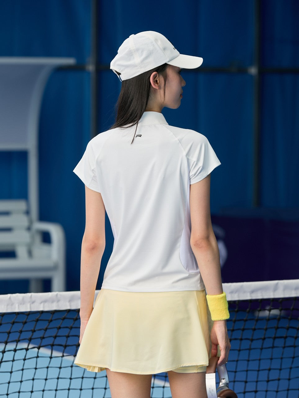 Cropped image of a female model wearing a white sleeveless top and Ramsports FlexTek Power Shorts in yellow, turned away from the camera