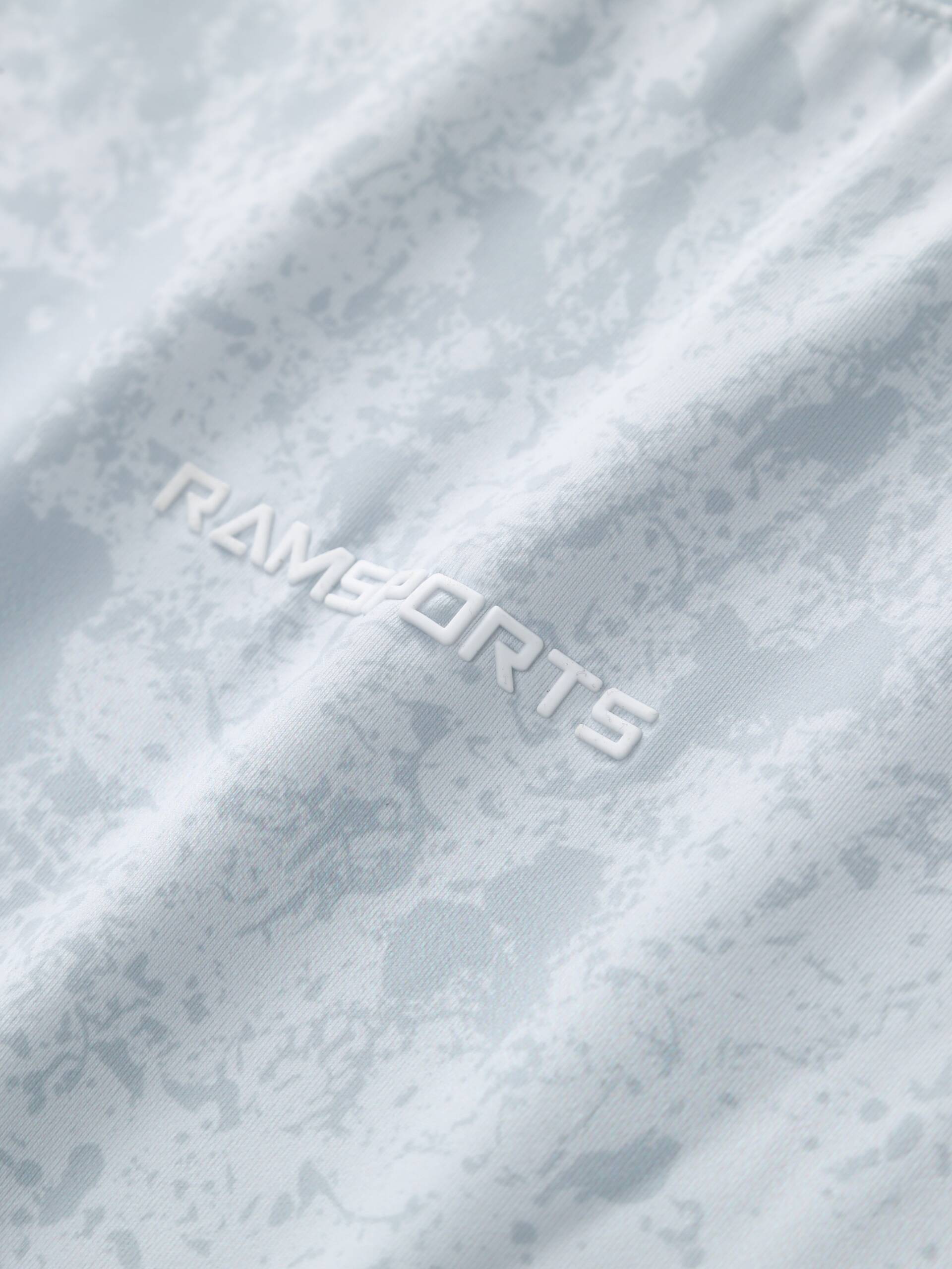 Close-up of the white Ramsports logo printed on the gray Ramsports CoolDry Marble Print Long-Sleeves Tee