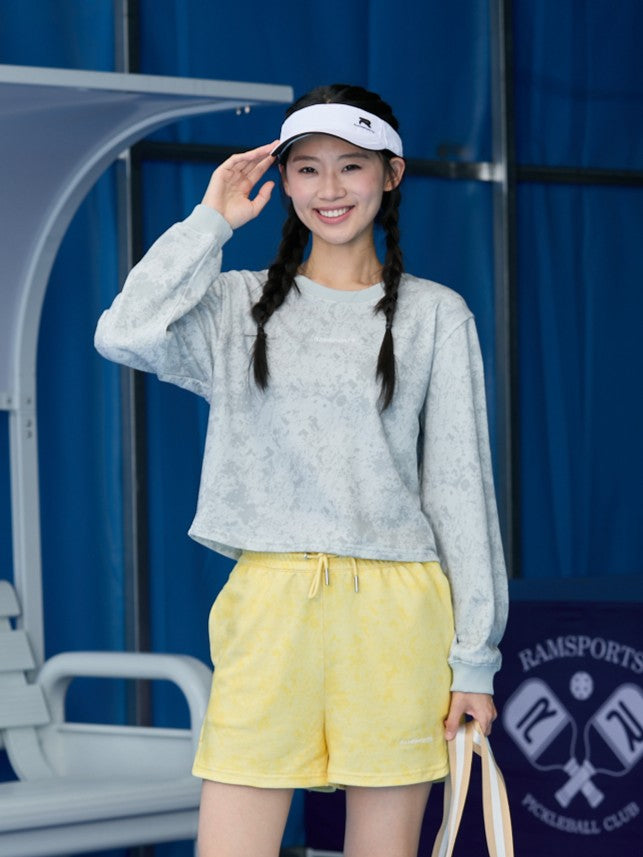 Smiling Asian model in yellow Ramsports EcoSoft Marble Print Shorts and a gray long-sleeve top