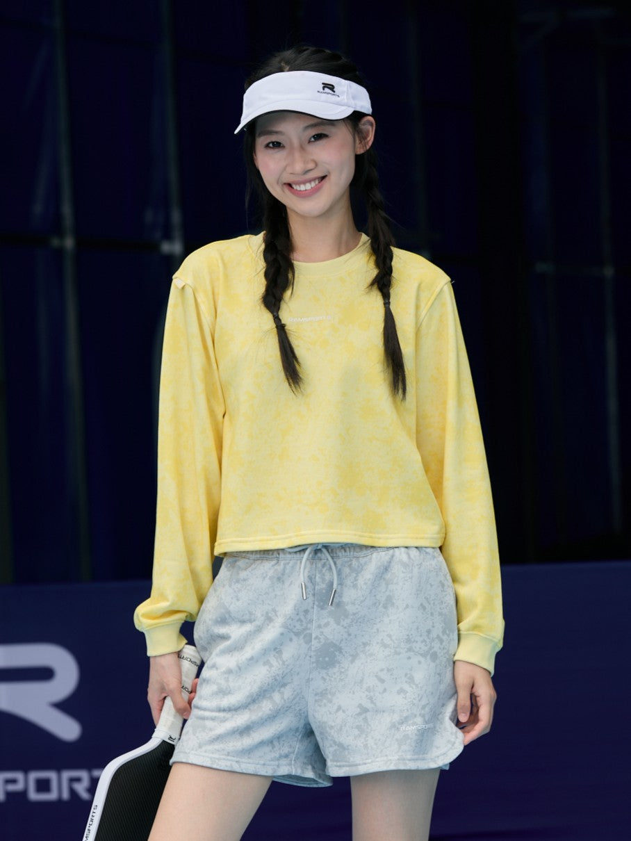 Smiling female model in a yellow long-sleeve top and Ramsports EcoSoft Marble Print Shorts in gray