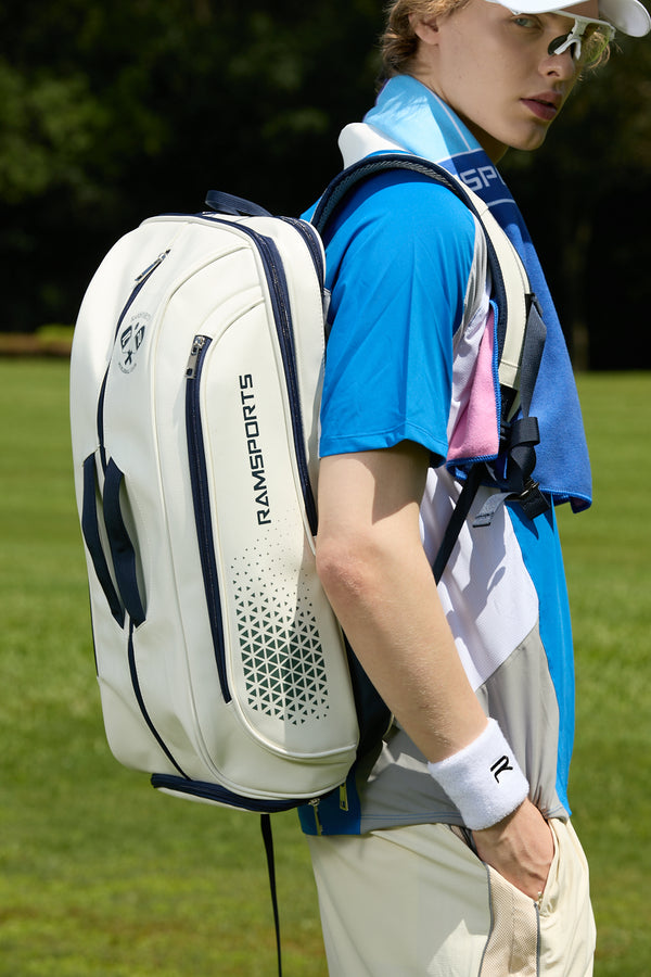 Male model in a blue shirt wearing the Ramsports Light Court Luxe Tot bag with one strap over his shoulder, with one hand in his pocket