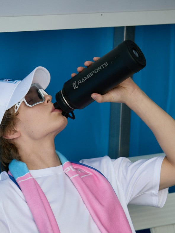  model sitting while drinking water from the Ramsports black tumbler