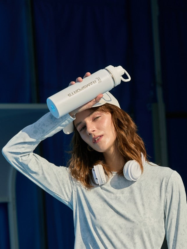 Cropped image of a female model holding a white Ramsports tumbler, posing as if wiping off sweat